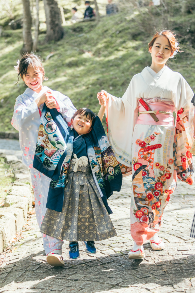 ママと長女と手をつなぎ高い高いをしてもらう3歳男の子