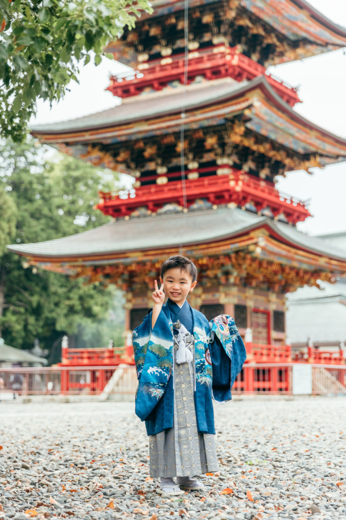 三重塔を背景にピースをする5歳男の子の七五三写真