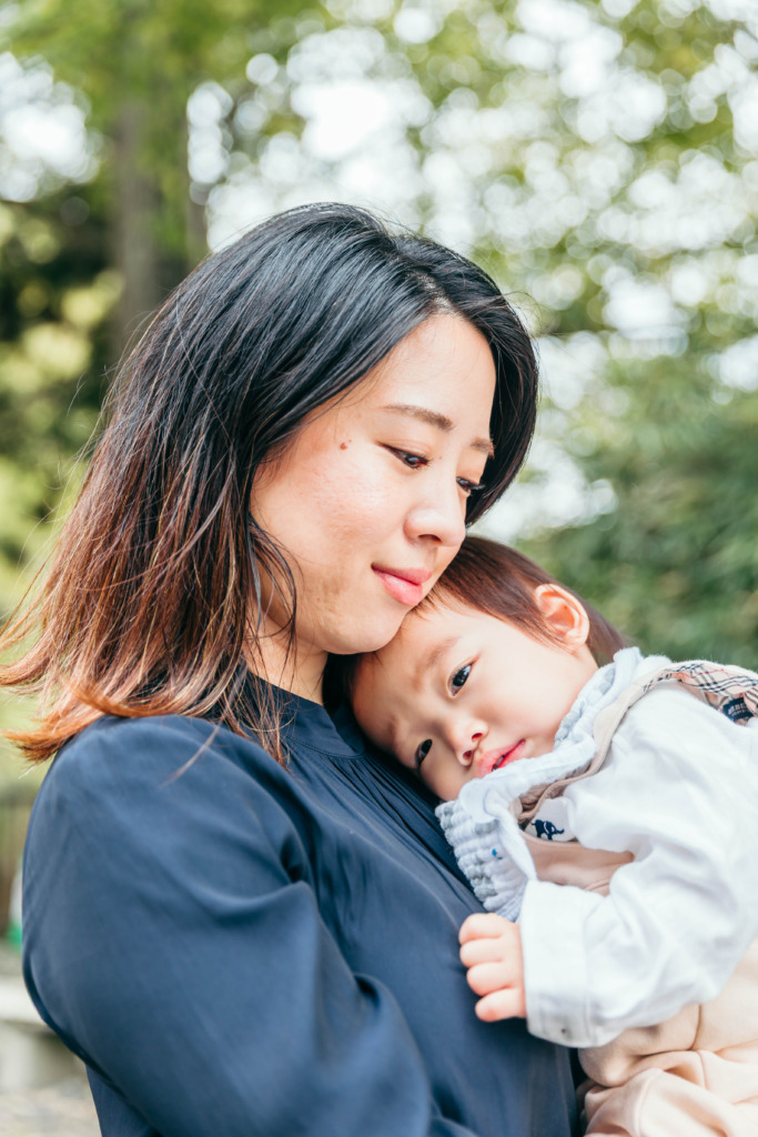 ママに抱っこされる小さなお子さまの自然な家族写真